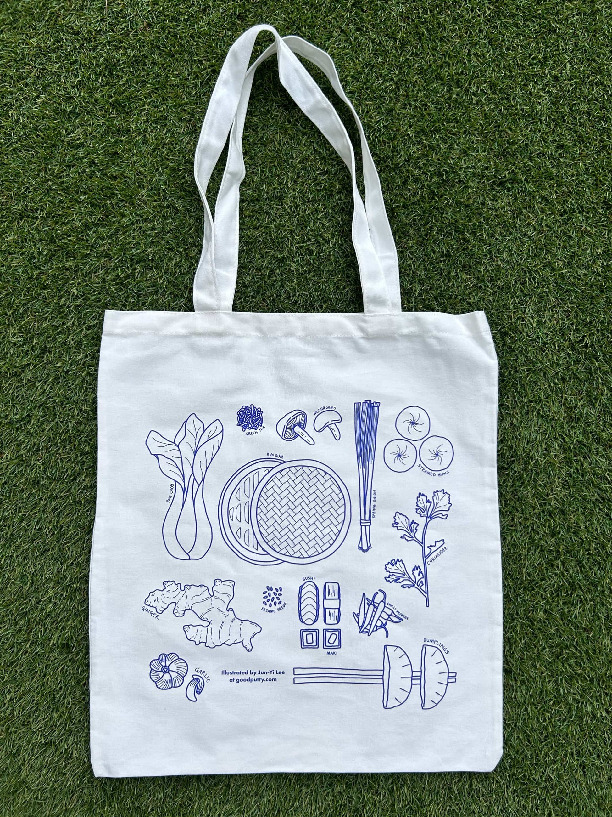 White tote bag with blue illustrations of Asian ingredients on a grass background