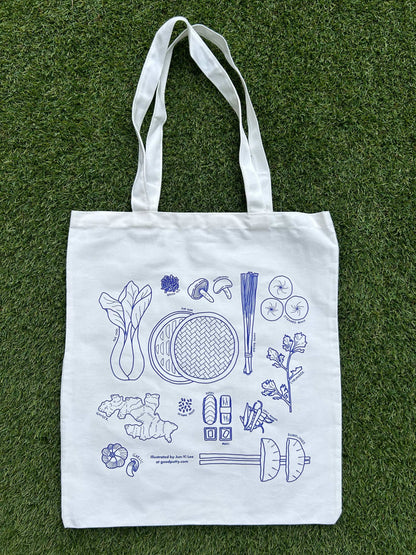 White tote bag with blue illustrations of Asian ingredients on a grass background