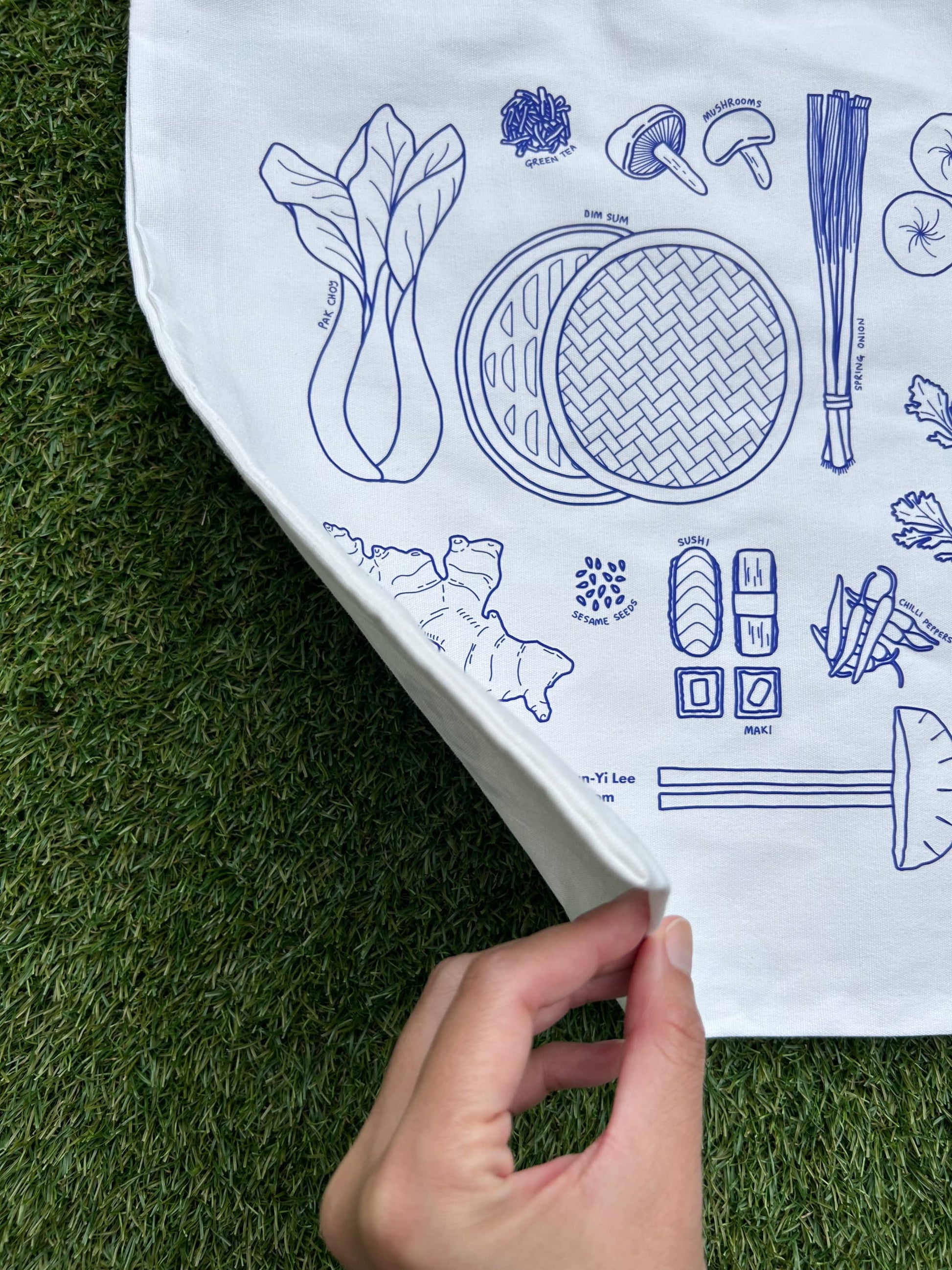 Closeup showing a white tote bag with blue illustrations of Asian ingredients
