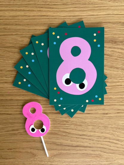 Number 8 birthday card with polka dots and a matching cake topper on a wooden surface