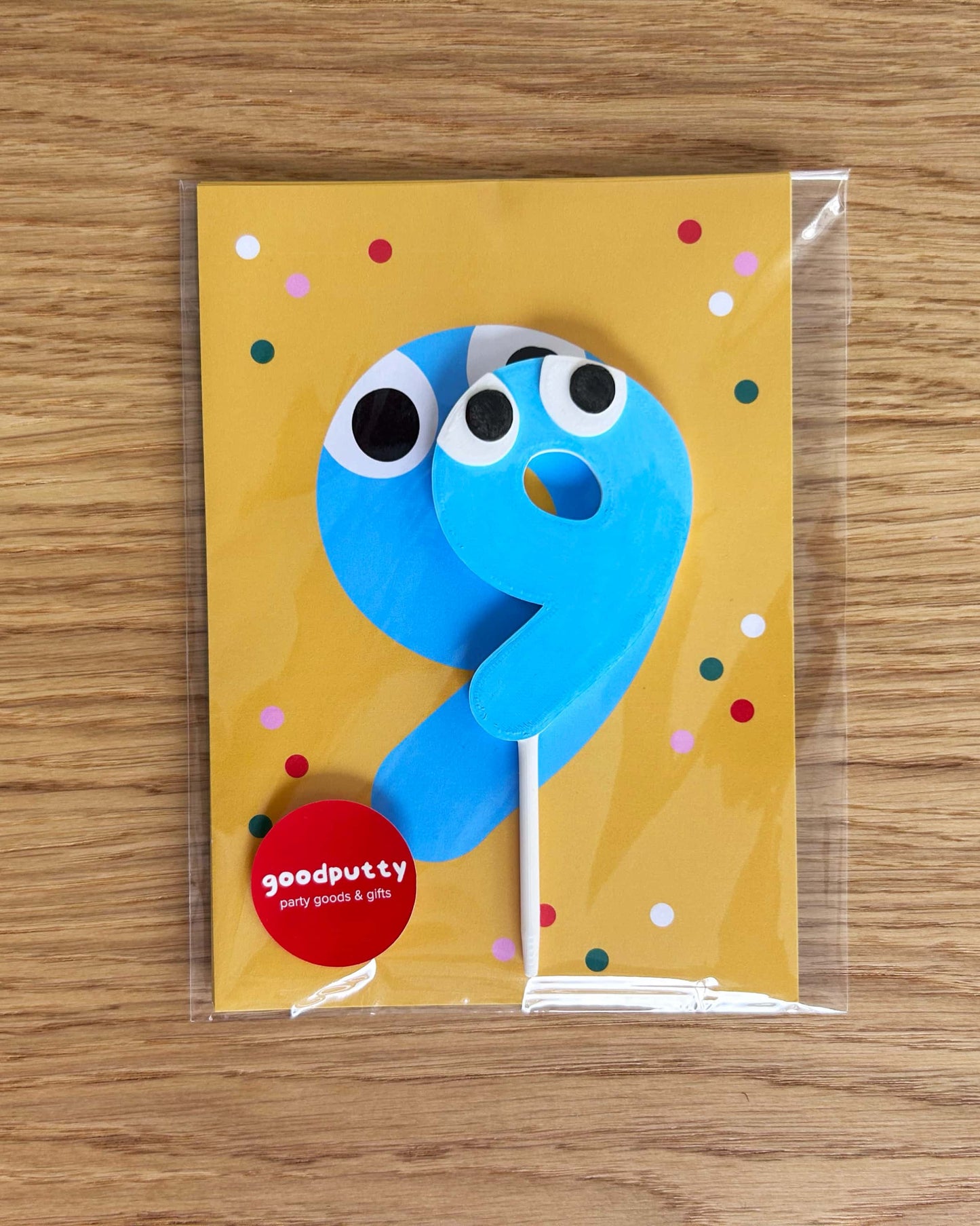 Blue number 9 cake topper on yellow cards with colorful dots