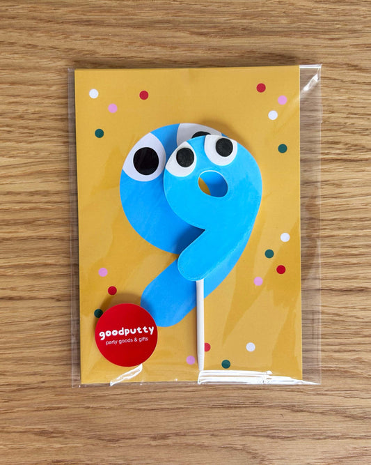 Blue number 9 cake topper on yellow cards with colorful dots