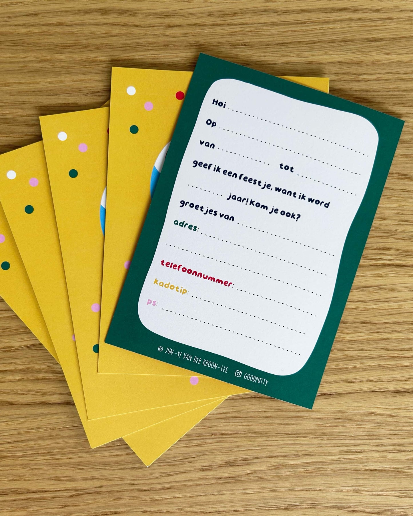 Set of colorful birthday invitation cards with a one card featuring text on a wooden surface