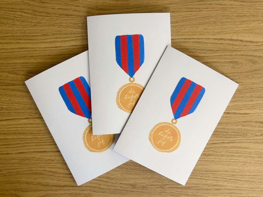 Three greeting cards with medal designs on a wooden surface