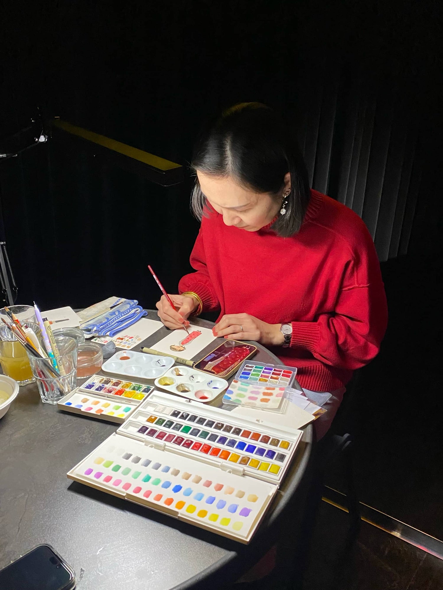 Jun-Yi in a red sweater painting with watercolors at a table at a Lunar New Year event in Rotterdam.