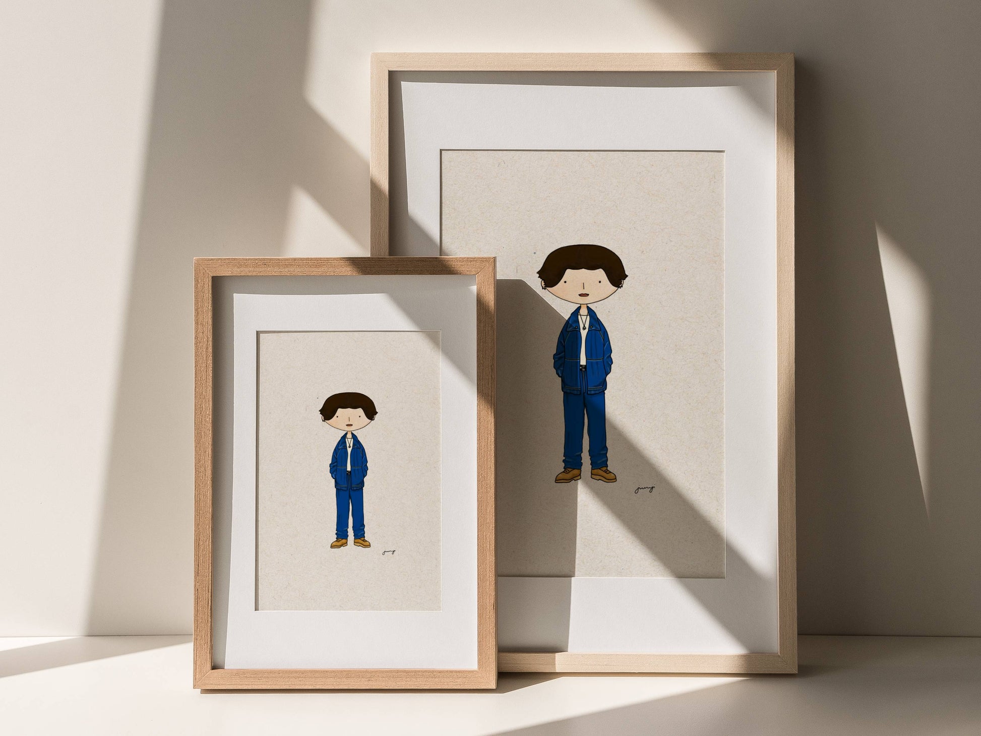 Two framed illustrations of Korean idol Jungkook in a suit on a light background