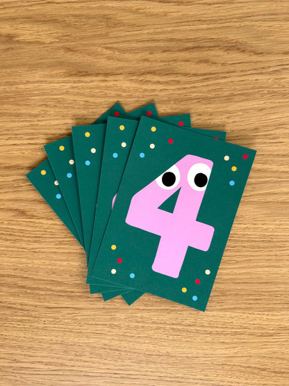 Stack of green birthday party invitations with a pink number 4 on a wooden surface