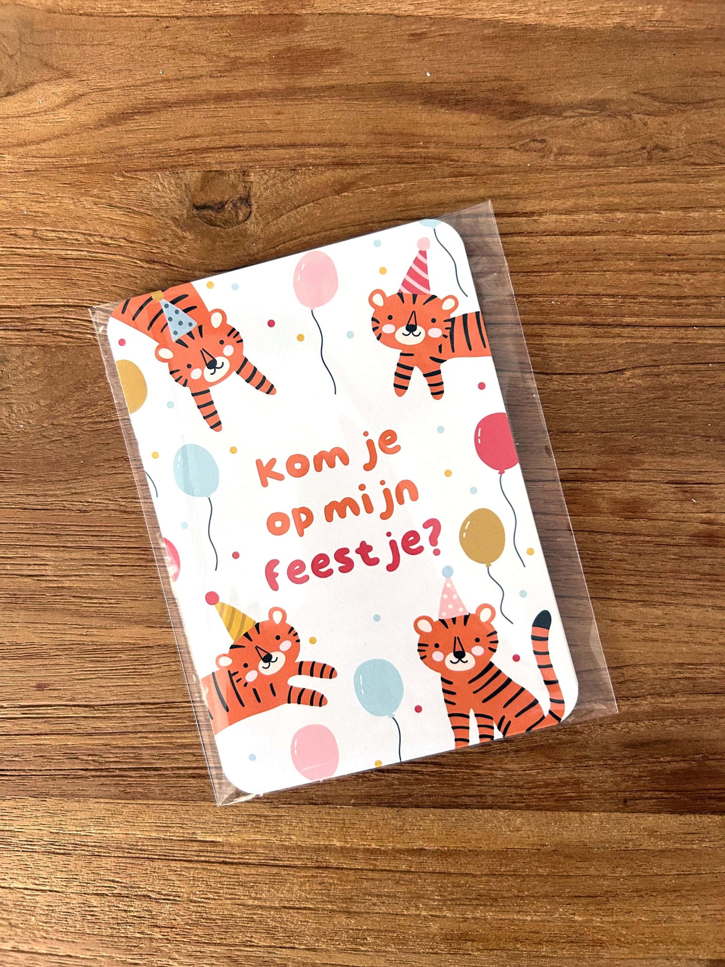 Card with illustrated tigers and party hats on a wooden surface