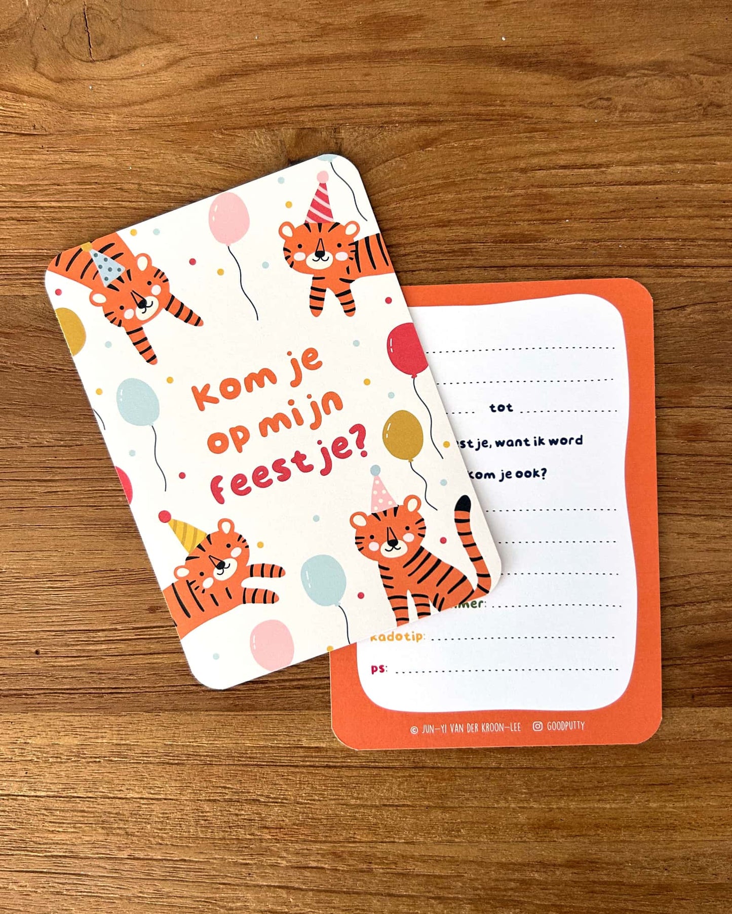 Two children's party invitations with tiger illustrations on a wooden surface