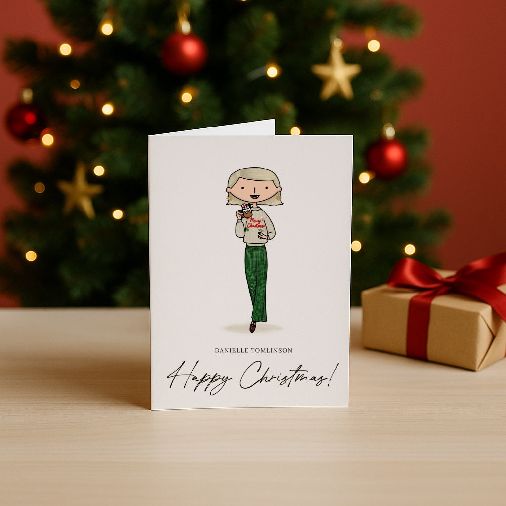 Christmas card with illustration of a lady holding a mug, in front of a decorated Christmas tree.