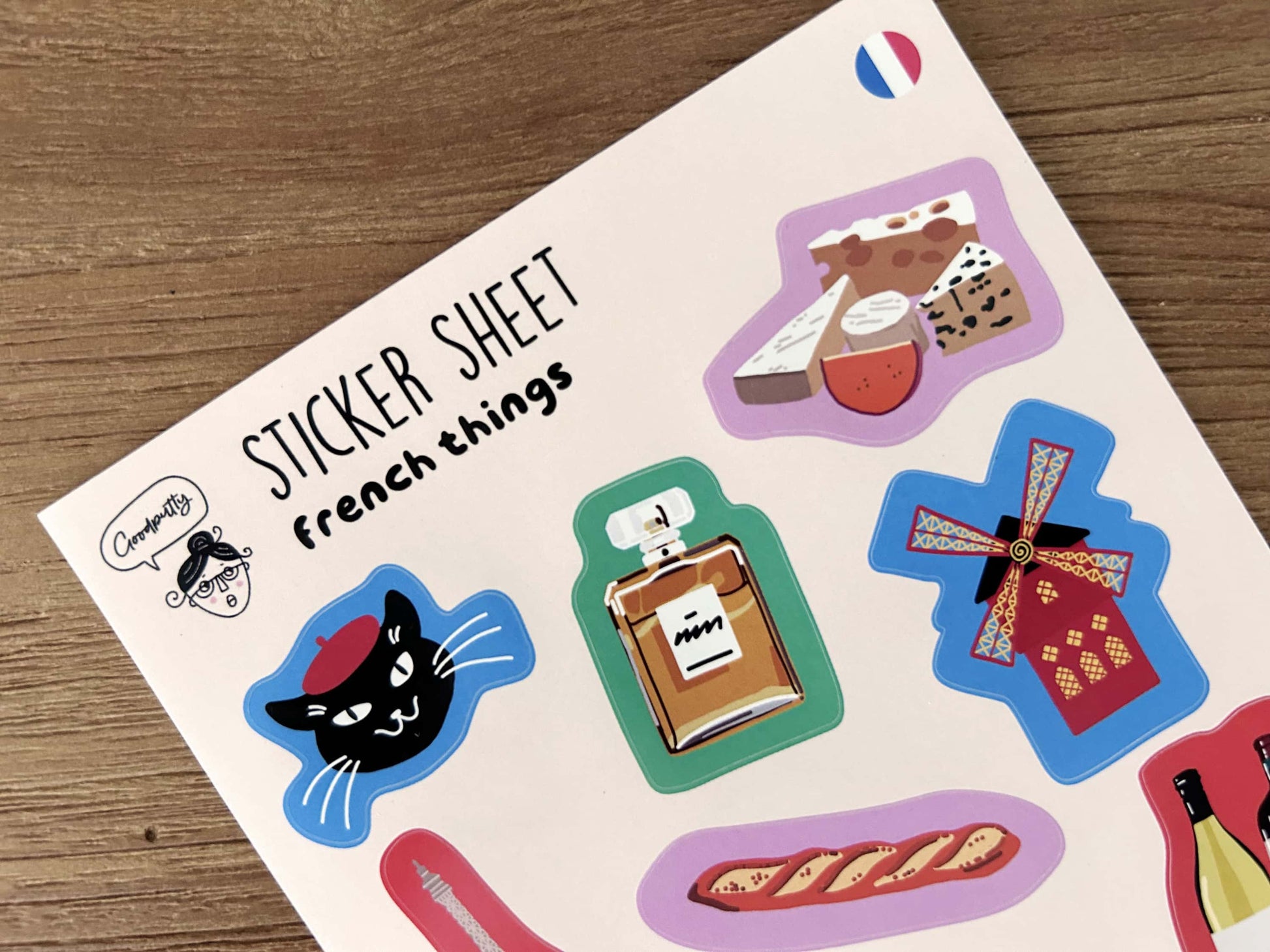 Sticker sheet with various French stickers on a wooden surface