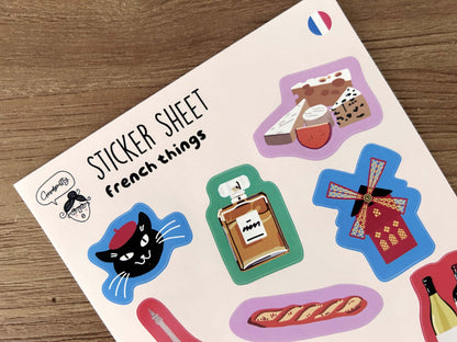 Sticker sheet with various French stickers on a wooden surface